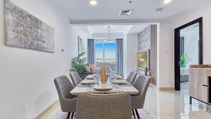 Un espace repas moderne avec une longue table dressée pour six personnes, entourée de chaises rembourrées.