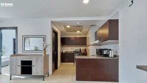 Une cuisine moderne avec des meubles de couleur sombre en bois, un plan de travail en marbre et un îlot central intégré.
