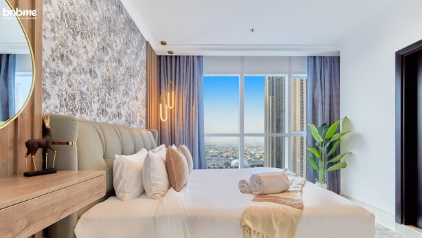 Une chambre d’hôtel moderne avec un grand lit, une table de chevet en bois, un miroir et une vue sur la ville.