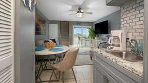 A compact kitchen with a dining area, a ceiling fan, a coffee maker, and a view to the outside.