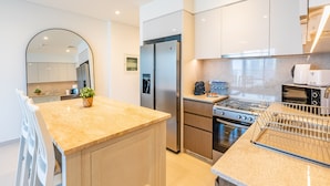 A modern kitchen with a central island, stainless steel appliances, and a large window. - Exquisite 2BR - Breathtaking BurjSkyline (Dubai)