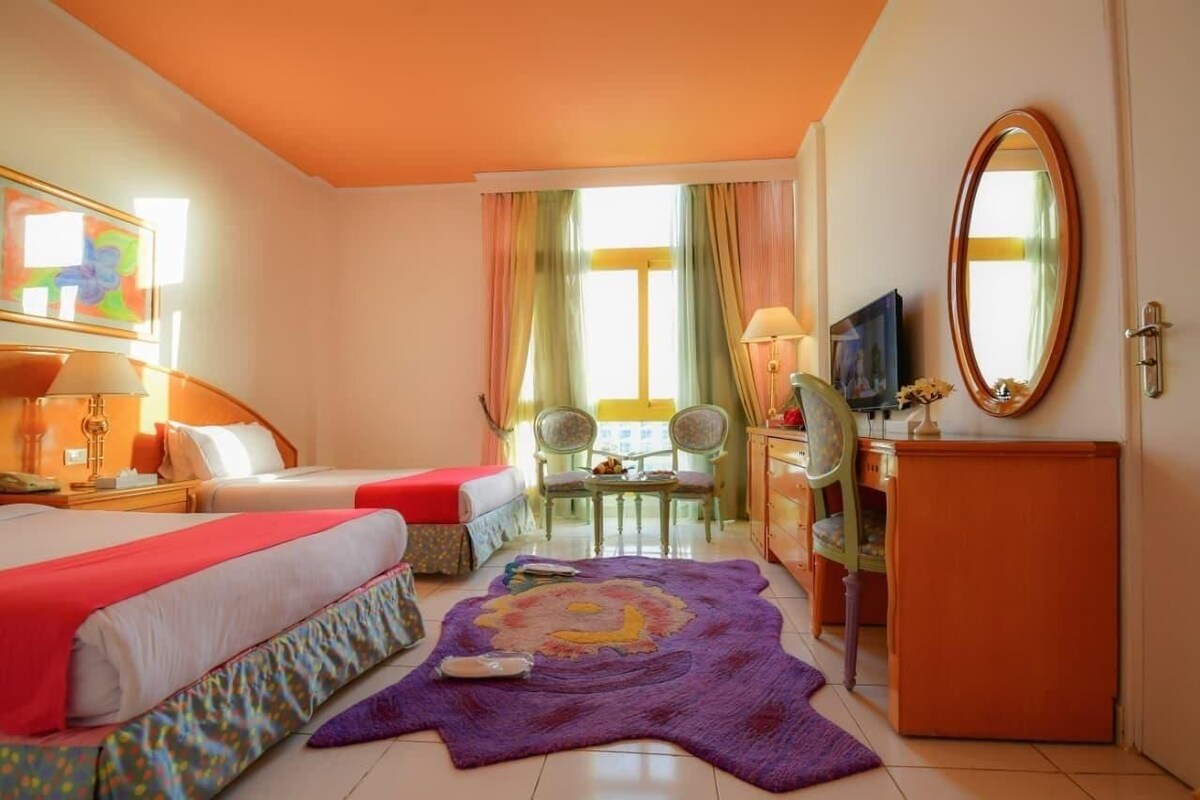 Habitació d'hotel amb dos llits, una taula, una cadira, una televisió i un mirall.