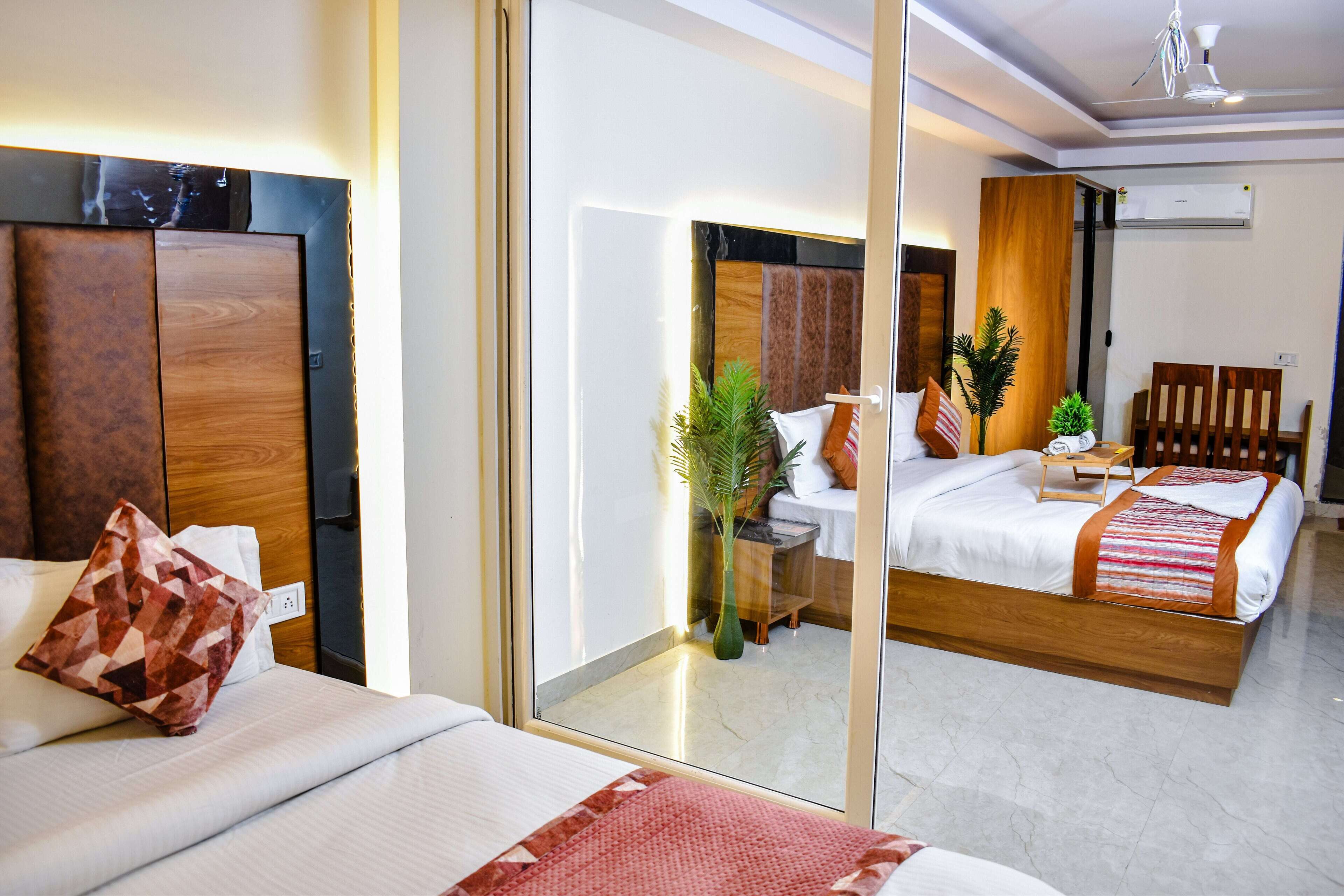 A hotel room with a large mirror, a bed with a wooden headboard, a bedside table with a lamp, and a chair.