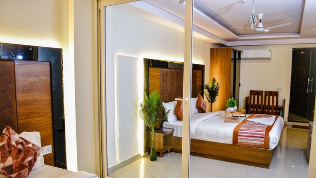 A modern hotel room with a large bed, a bedside table, a mirror, and a ceiling fan. - HOTEL YASH PALACE (New Delhi)