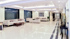 A spacious lobby with a high ceiling, recessed lighting, and a central seating area with sofas and a coffee table. - HOTEL YASH PALACE (New Delhi)