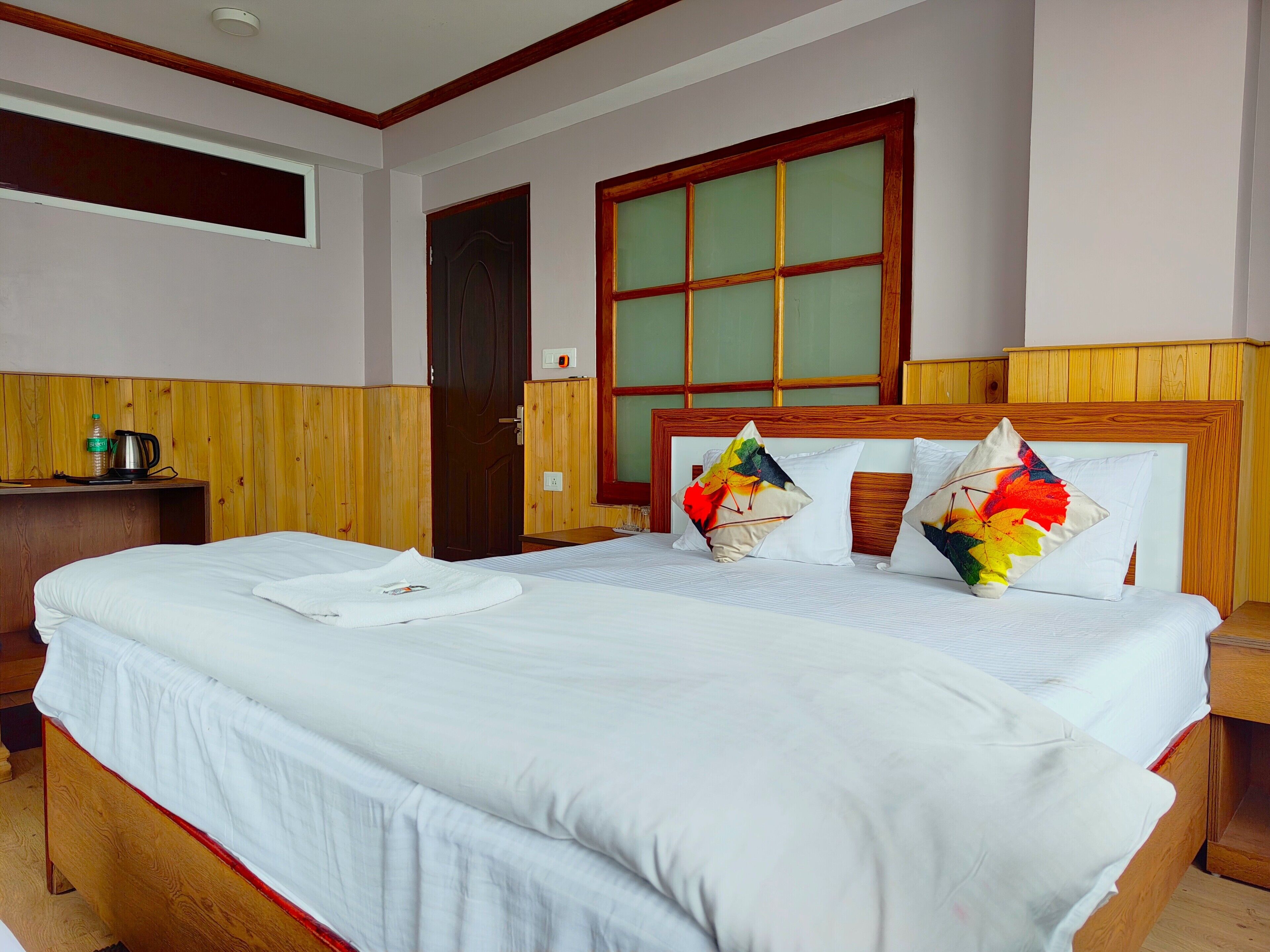 A hotel room with a large bed, wooden headboard, and a window with wooden frames.