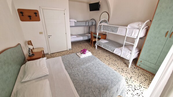 A dormitory room with bunk beds, a desk, a chair, a small table with a lamp, and a mirror. - Hotel Bellavista (Forio)