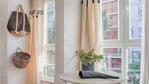 A room with a white table, a hanging woven bag, a potted plant, and a window with curtains. - GuestHouse by Trip2Portugal (Lisbon)