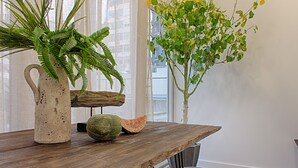 A wooden table with a pitcher of ferns and a watermelon. - GuestHouse by Trip2Portugal (Lisbon)