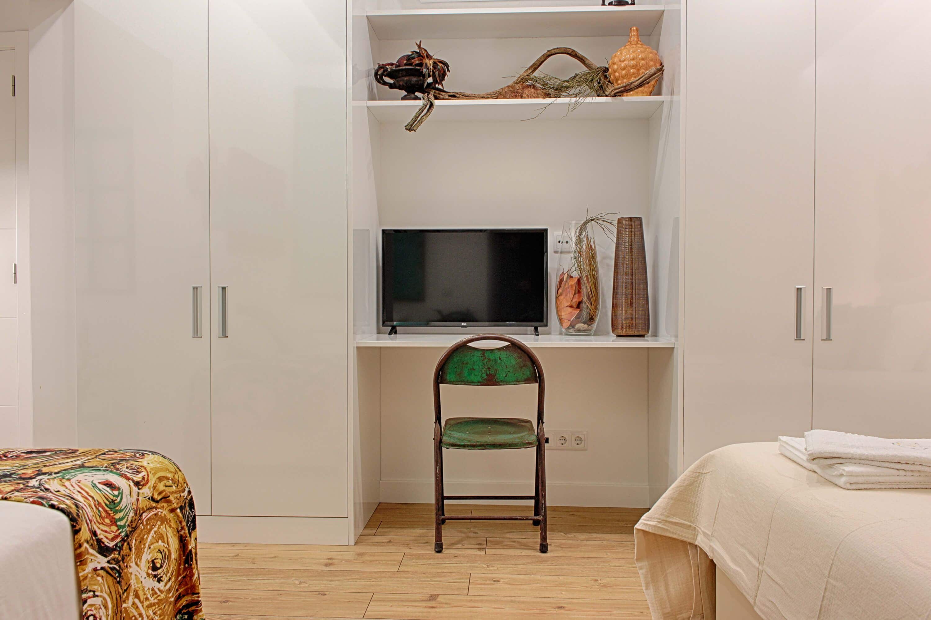 Une chambre à coucher avec un lit, une chaise, un téléviseur et une armoire.