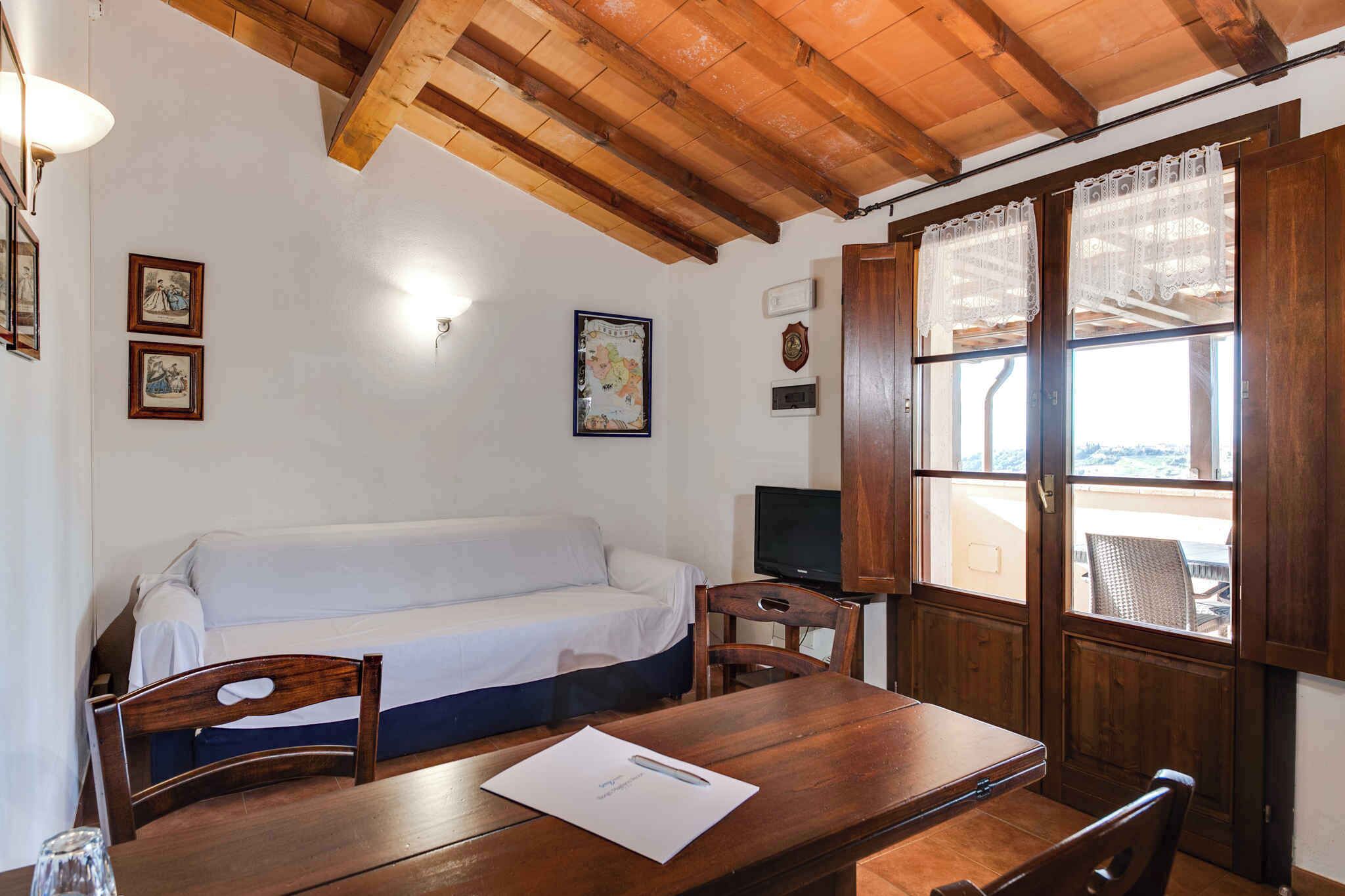 A room with a wooden ceiling, a white sofa, a wooden table, a TV, and a window with lace curtains.