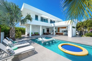 Ein modernes Haus mit Swimmingpool, Gartenmöbeln und einer Terrassenanlage.