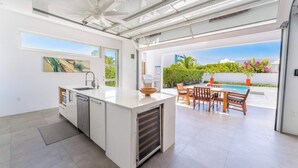 Een moderne keuken met een groot eiland, een zithoek buiten en uitzicht op een zwembad.