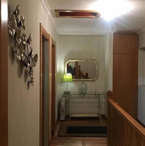 Un corridoio con una porta in legno, uno specchio, una vetrina e una lampada.