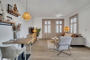 A modern living room with a dining area, a sofa, a TV, and a ceiling fan.