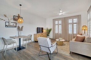 En moderne stue med sofa, sofabord, fjernsyn og et spiseområde med stole og bord.