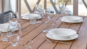 A wooden table set with white plates, clear glasses, and wine glasses, indicating a dining area.