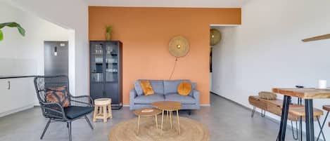 Ein modernes Wohnzimmer mit einer Couch, einem Sessel, einem kleinen Tisch und einem Deckenventilator.