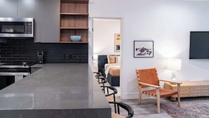 Eine moderne Küche mit Kochinsel, Mikrowelle und Spüle. Es gibt eine Sitzecke mit einer Couch und einem Sessel.