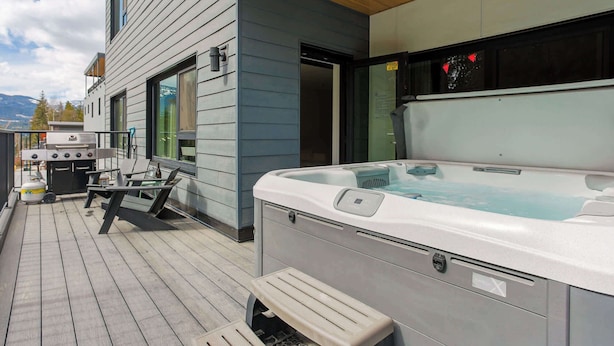 Ein Whirlpool auf einer Holterrasse, ein Grill und ein Patio-Tisch.