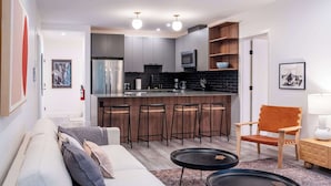 Eine moderne Küche mit grauen Schränken, einer zentralen Kochinsel mit Hockern, einer Mikrowelle und einer Kaffeemaschine.