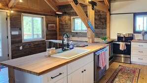 Eine rustikale Küche mit Holzbalken, einer großen Kochinsel mit Spüle und einem Edelstahlbackofen.