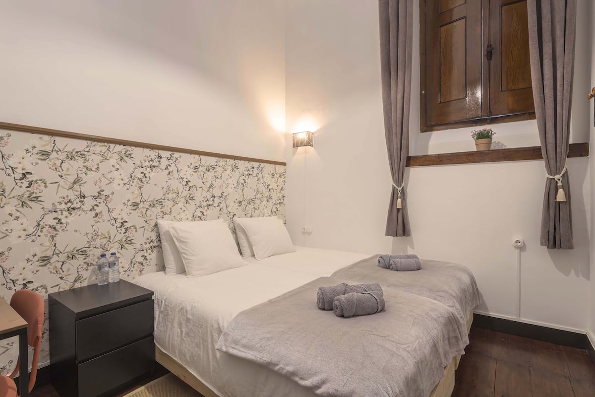 Quarto com cama, mesa de cabeceira e luminária.
