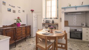 A compact kitchen with a dining table, a refrigerator, a microwave, and an oven. - Happy Holiday Sintra (Sintra)