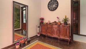 A room with a wooden cabinet, a large mirror, a clock, and potted plants. - Happy Holiday Sintra (Sintra)
