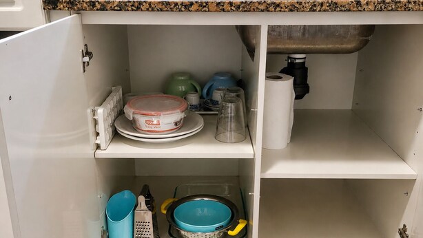 Una cocina con escurreplatos, hervidor, cafetera y cubo de basura.