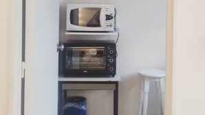 Une petite cuisine équipée d’un four à micro-ondes et d’un grille-pain, le tout installé sur une petite étagère.