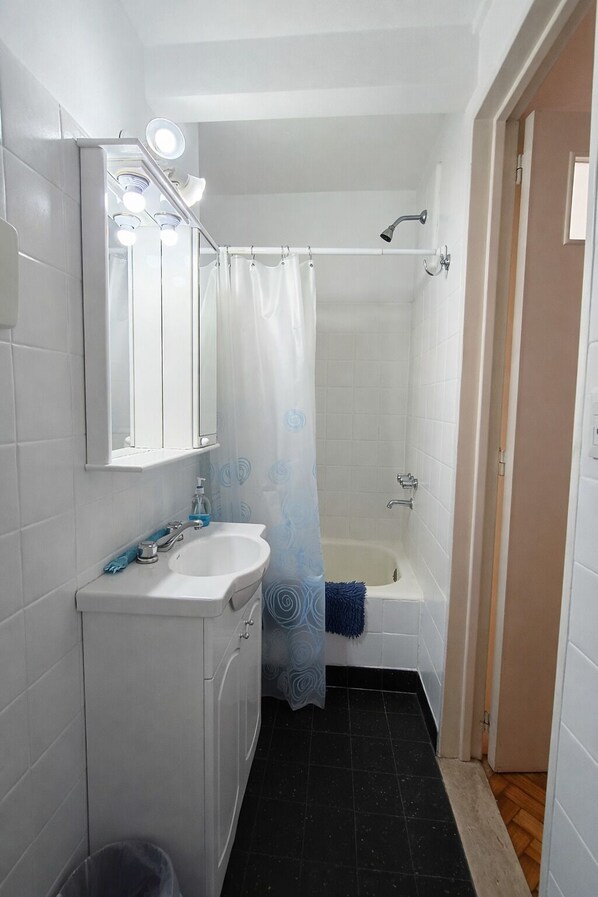 Een badkamer met een wit wastafelmeubel, spiegel en douchegordijn.