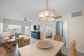 Relax in this spacious living area with a dining table, comfortable seating, and a large television.