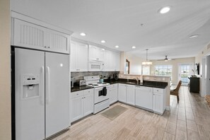 Enjoy cooking in this well-equipped kitchen with appliances, a sink, and a window for natural light.