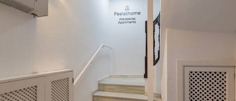 A staircase in a building with a sign reading "Feelathome Atarazanas Apartments."