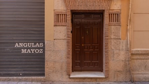 A brown door with a small step leading up to it, set in a beige wall with a brick pattern above. - Feelathome Atarazanas Apartments (Málaga)
