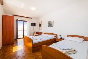 A hotel room with two wooden beds, a wooden wardrobe, a television, and a painting on the wall.