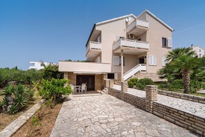A multi-story residential building with a stone-paved courtyard, outdoor seating, and a staircase leading to the upper floors.