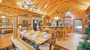 A wooden cabin interior with a dining area, kitchen, and a view of the outside. - Deer's Lair Cabin in Cedar Falls Resort - 4 bedroom, 3.5 bathroom, game room (Sevierville)