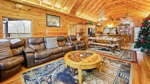 A cozy log cabin interior with a leather sofa, a round coffee table, and a dining area with wooden furniture. - Deer's Lair Cabin in Cedar Falls Resort - 4 bedroom, 3.5 bathroom, game room (Sevierville)
