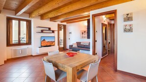 A spacious dining area with a wooden table and chairs, a large window with curtains, and a view of the outdoors.