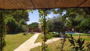 A backyard with a paved pathway leading to a wooden gate, surrounded by greenery and a swimming pool. - Holiday Home Le Dali in Piolenc, in Complete Tranquility (Piolenc)