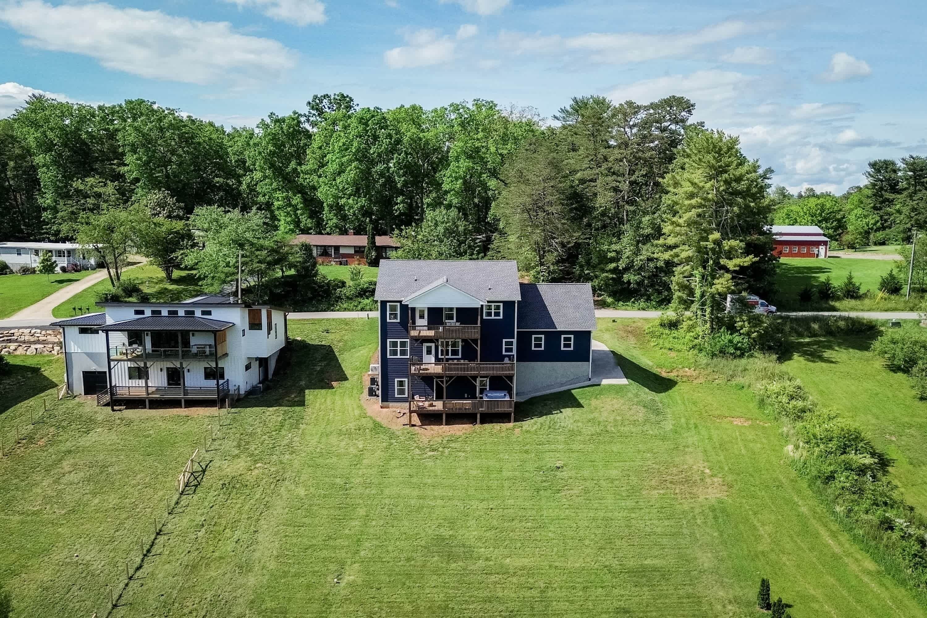 A large two-story house with a balcony and a covered porch, surrounded by a well-maintained lawn and trees.