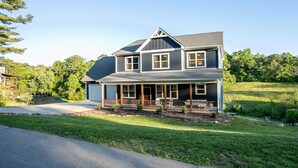 A two-story house with a front porch, a garage, and a well-maintained lawn. - Serene Luxury Retreat| Hot Tub|Views (Weaverville)