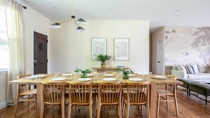 A dining area with a wooden table set for six, surrounded by wooden chairs, with a ceiling light fixture above. - Serene Luxury Retreat| Hot Tub|Views (Weaverville)