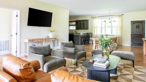 A spacious living room with a sofa, armchairs, and a coffee table. A flat-screen TV is mounted on the wall. - Serene Luxury Retreat| Hot Tub|Views (Weaverville)