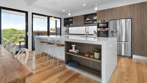 A modern kitchen with a central island, stainless steel appliances, and a large window overlooking greenery. - MAGNIFICENT MAX | SUPERB HOLIDAY LUXURY | ST ANDREWS BEACH | OCEANSIDE | GOLF (St Andrews Beach)