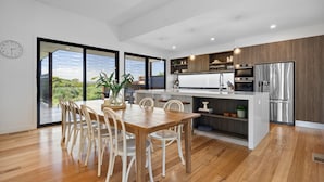 A modern kitchen with a central island, wooden flooring, and large windows offering a view of greenery. - MAGNIFICENT MAX | SUPERB HOLIDAY LUXURY | ST ANDREWS BEACH | OCEANSIDE | GOLF (St Andrews Beach)