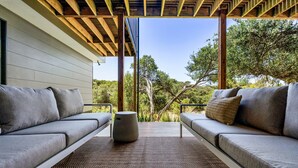 A covered outdoor seating area with two grey sofas and a woven rug, overlooking a natural landscape. - MAGNIFICENT MAX | SUPERB HOLIDAY LUXURY | ST ANDREWS BEACH | OCEANSIDE | GOLF (St Andrews Beach)