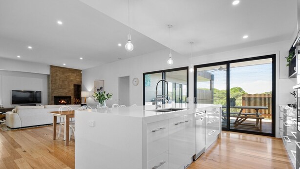 A modern kitchen with a central island, a dining area with a sofa and table, and a large window offering a view of the outdoors. - MAGNIFICENT MAX | SUPERB HOLIDAY LUXURY | ST ANDREWS BEACH | OCEANSIDE | GOLF (St Andrews Beach)